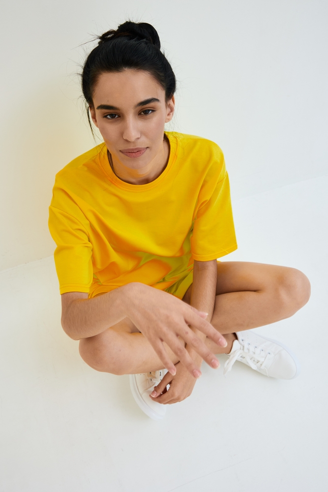young,woman,sitting,casually,wearing,a,bright,yellow,t shirt,and